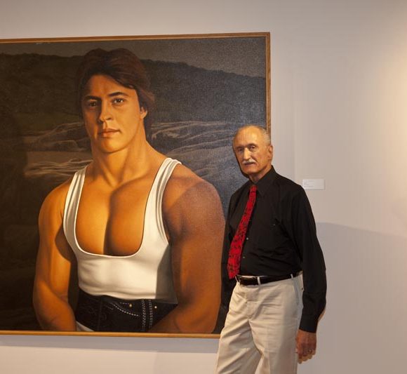Bill Wiman standing in front of his painting of a bodybuilder in the Teresa Lozano Long Art Gallery, in the main lobby.