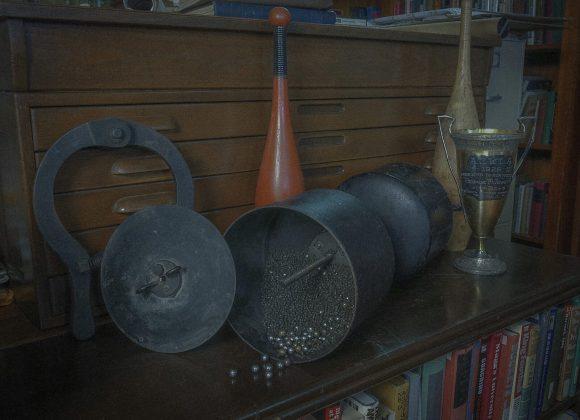 A horseshoe, two Indian clubs, a Milo Adjustable Barbell and an American Continental Weight-Lifters Association (ACWLA) trophy.