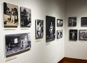 A photograph of walls in the Strength & Friendship exhibit show black and white photos from the Tommy Kono collection.
