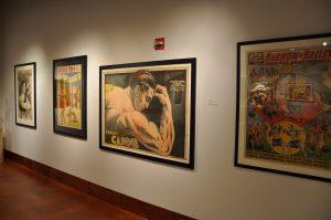 Four strongman and circus posters, including ones for Ruy da Cunha, the Apollo Trio, Ernest Cadine and Barnum and Bailey's Circus, all from the Todd Poster Collection, in the Teresa Lozano Long Art Gallery, in the main lobby.