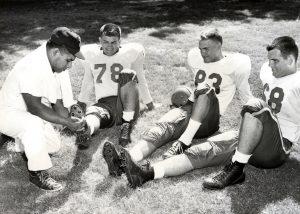 Former African American University of Texas football trainer Frank Medina helping three Texas football players