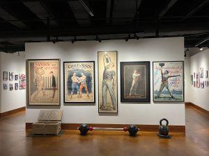 View of the Stark* Art exhibit showing posters of strongmen like Sandow and Irving