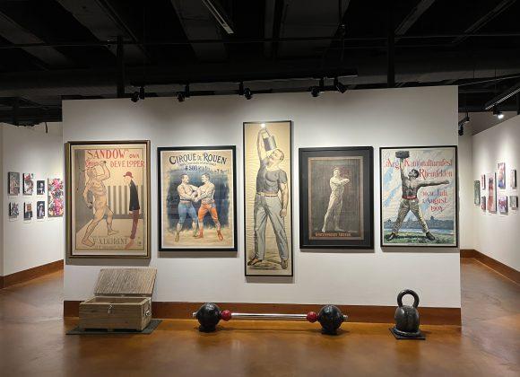 View of the Stark* Art exhibit showing posters of strongmen like Sandow and Irving