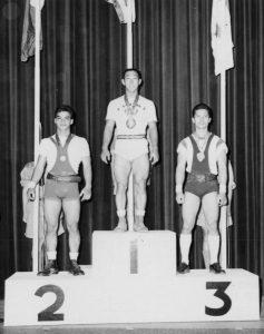 A black and white photo where Walter Imahara stands in the first place position on a podium.
