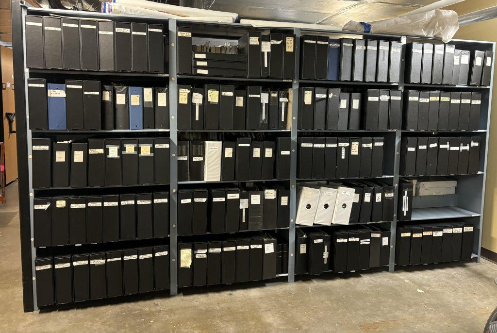 Six foot high shelves by twelve foot wide shelves in the archives filled with black binders containing hundreds of photos of University of Texas athletes, teams, coaches, action, and staff.