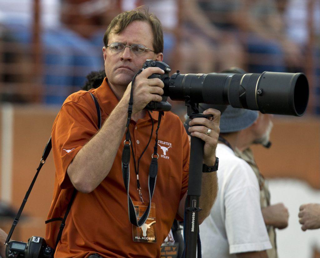 A color photo of Jim Sigmon intensely photographing a UT football game.