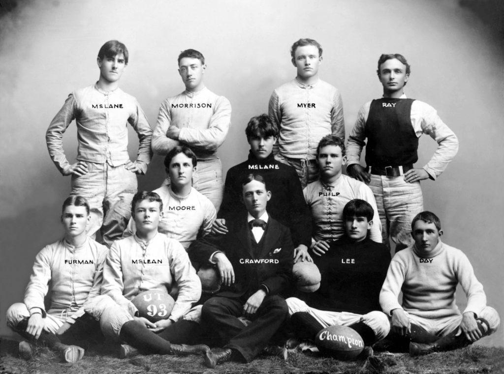 A black and white photo of the 1893 University of Texas Football team: 12 white men, nine of whom where white uniforms, one wears a suit, and two wear black turtle neck sweaters.