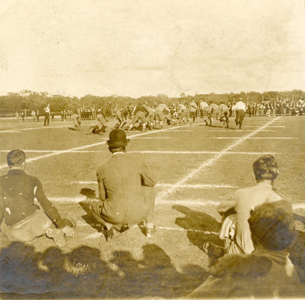 A black and white photo of football being played between Texas and Texas A&M, the angle looks level out onto the field at the line of scrimmage.