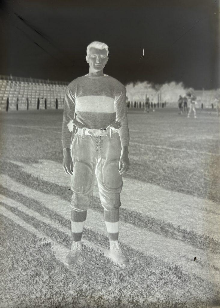 1914 glass positive plate of football player Bert Walker in his uniform posing on the field.