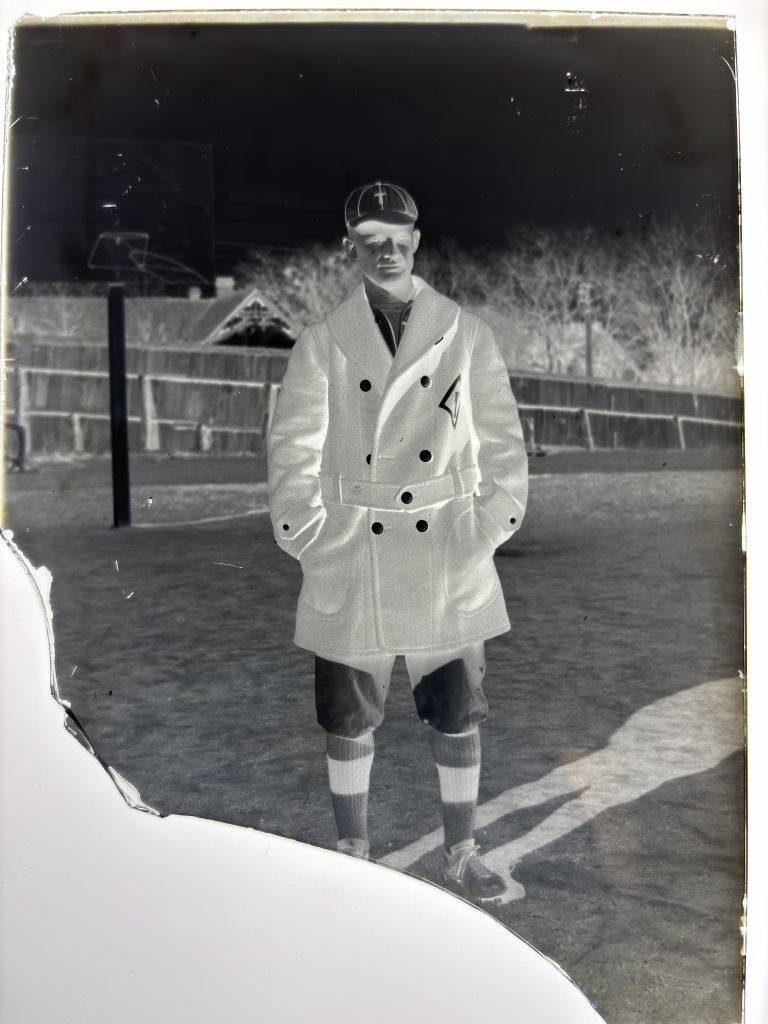 A glass positive plate broken at an angle at the bottom of University of Texas baseball player Tilly Anderson in 1915 wearing his peacock baseball coat and uniform.