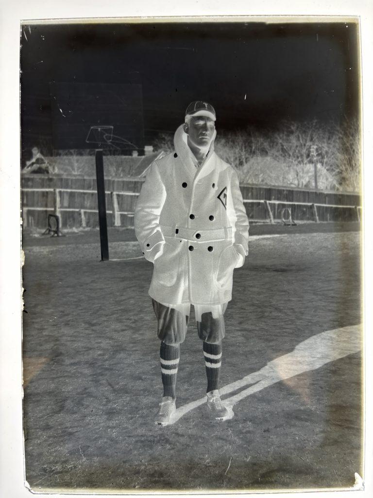 1915 glass positive plate of Mike Massey in his baseball peacock coat and uniform posing on the field.