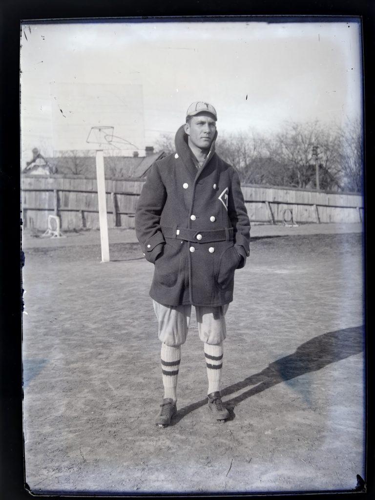 1915 image of Mike Massey in his baseball peacock coat and uniform posing on the field.