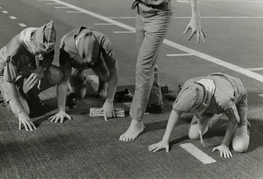 a black and white photo of boy scouts feeling the new astroturf field at Texas Memorial Stadium in 1969