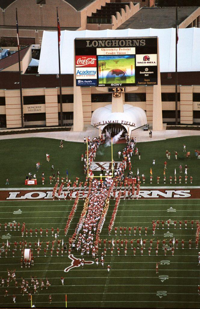 An aerial color photo of Texas Memorial Stadium in 1989 as the Longhorn football team takes the field.