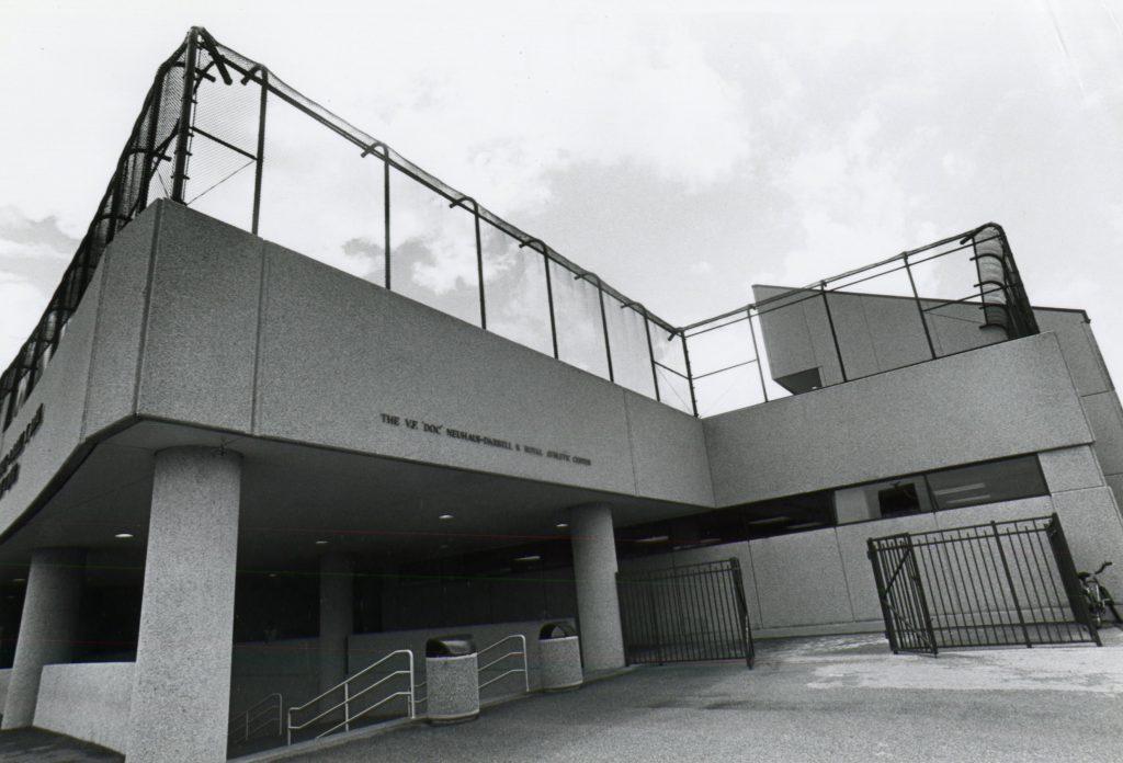 Black and white photo of the Neuhaus - Royal Athletic Center, a concrete edifice with chain link fence on roof.