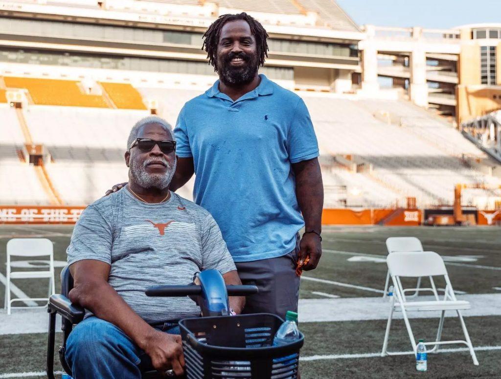 A color photo of Earl Campbell (seated) and Ricky Williams standing together on the newly named Campbell-Williams Field at DKR Texas Memorial Stadium