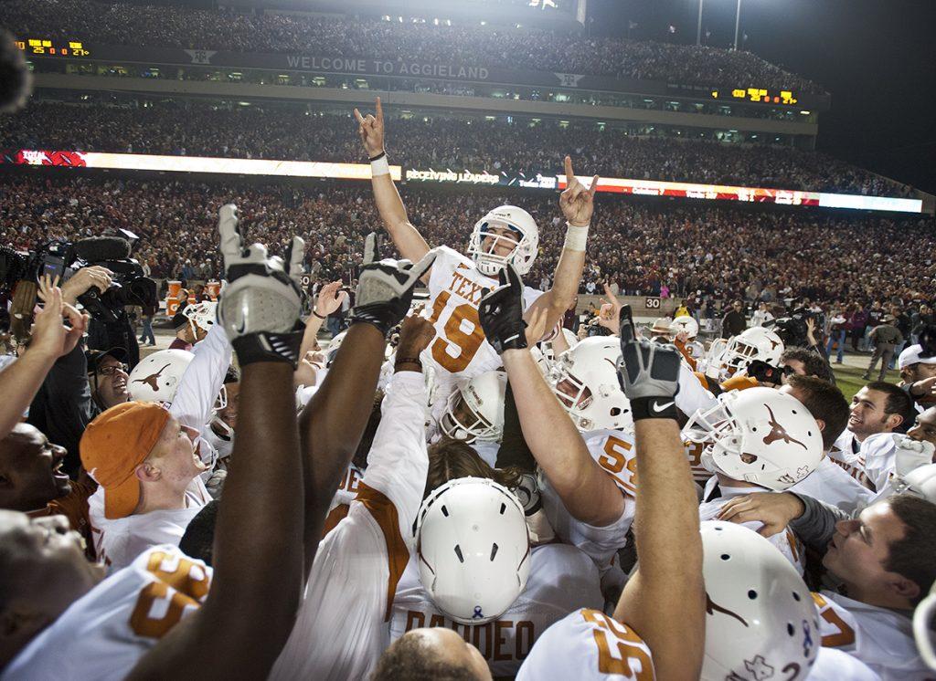 The University of Texas Longhorn football team, in white uniforms, holds up kicker Justin Tucker in celebration of his game winning field goal kick.