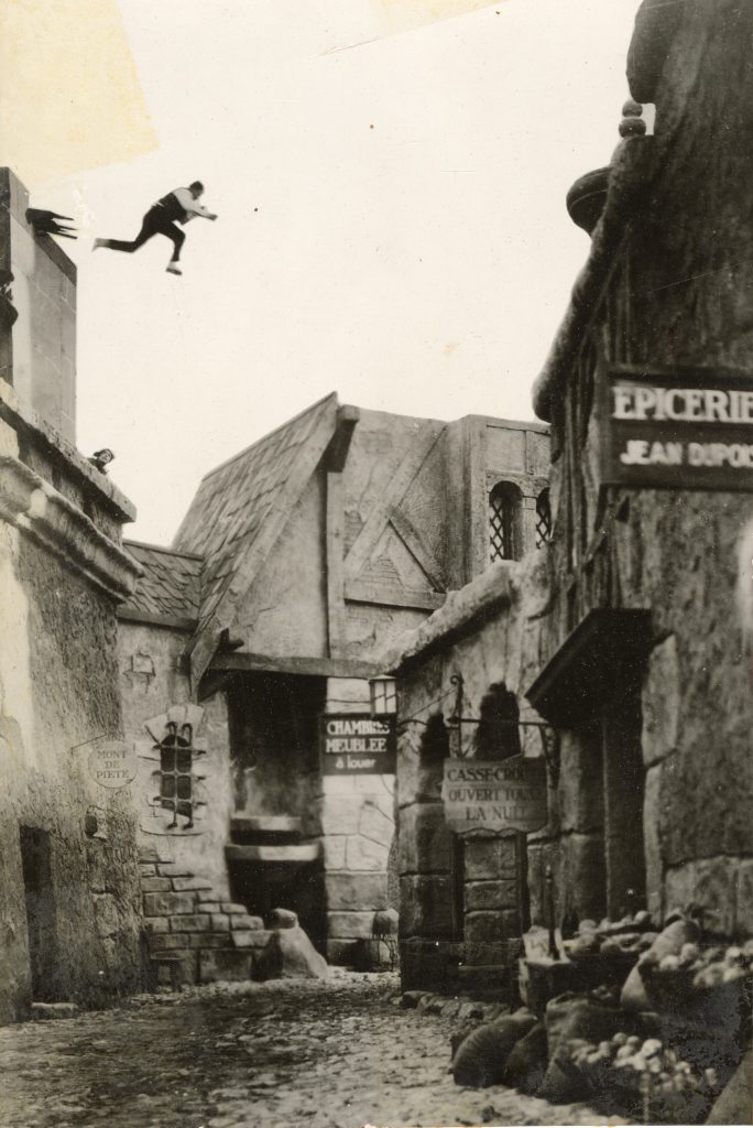 Joe Bonomo jumping from roof as men looks on.
