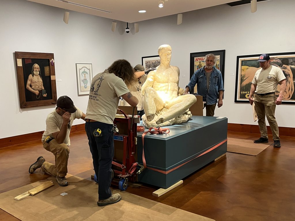 Sheehy Fine Art Services crew dolly the pedestal with Dionysus into place in the Stark Center Fine Arts Gallery.