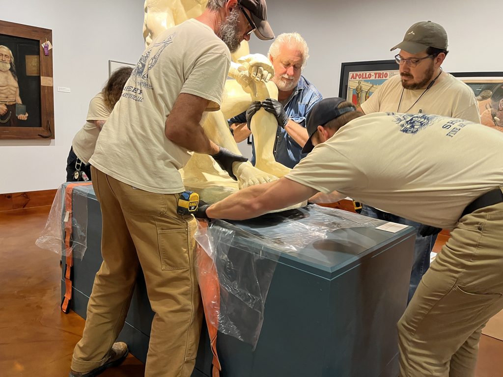Sheehy Fine Art Services crew lift The Seated Boxer from its pedestal in order to place special plastic sheeting under its base.