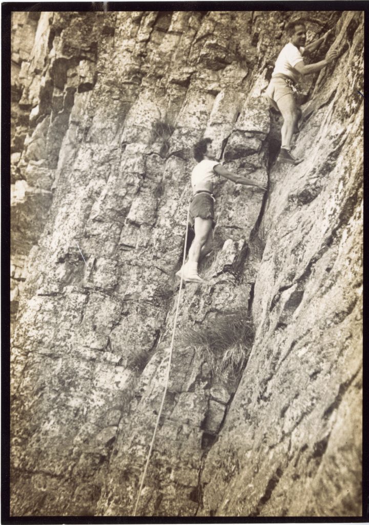 Bonnie Prudden and Dr. Hans Kraus climbing. Bonnie has a rope tied around her waist. 
