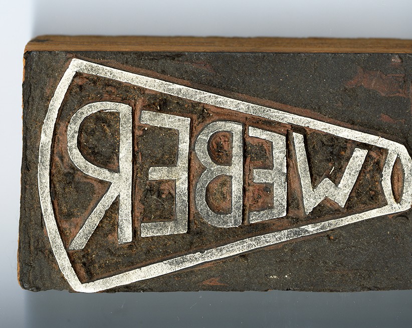 A hand carved stamp with megaphone and last name 'Weber.'